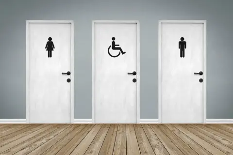 Trois portes blanches avec des pictogrammes : femme, homme et une porte pmr au centre.