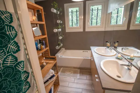 Salle de bain moderne avec baignoire, double vasque et étagères en bambou. Une idée pour relooker meuble salle de bain avec des plantes suspendues.