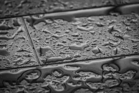 Gouttes d'eau sur un carrelage qui se décolle, signe d'une humidité persistante.