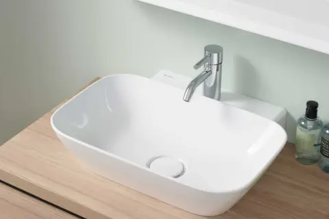Lavabo blanc moderne sur meuble en bois, robinetterie chromée. La hauteur du lave-main wc est idéale pour un usage confortable.