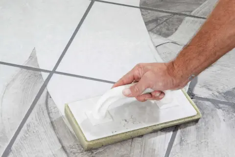 Main tenant, quand nettoyer carrelage après joint, utilise une éponge pour enlever l'excès de mortier.