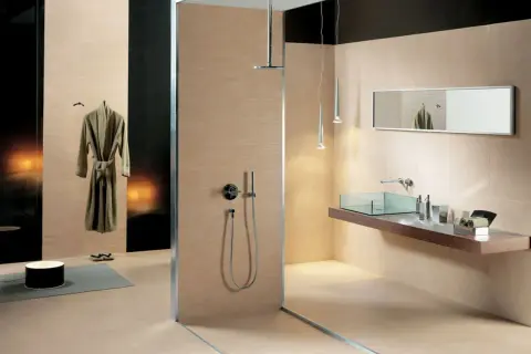 Salle de bain moderne avec douche vitrée, lavabo en verre, miroir et peignoir suspendu. Les carrelages respectent la norme PEI pour une durabilité accrue.