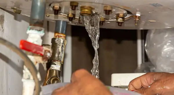 Fuite d'eau au niveau du ballon d'eau chaude, un plombier intervient pour l'entretien.