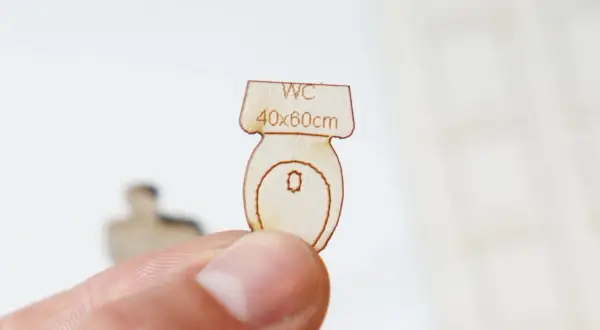 Miniature en bois d'une cuvette de WC, indiquant "WC 40x60cm", une suggestion pour la largeur minimum wc.