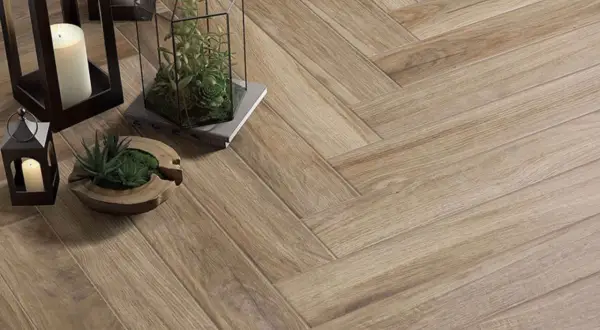 Un sol en pose carrelage en chevron, orné de lanternes, bougies et plantes, crée une ambiance chaleureuse et naturelle.