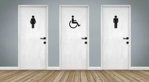 Trois portes blanches avec des pictogrammes : femme, homme et une porte pmr au centre.
