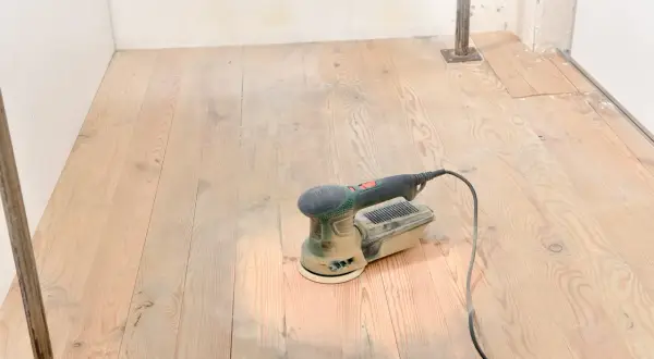 Outil de ponçage bois posé sur un parquet clair, prêt à lisser les planches.