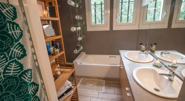 Salle de bain moderne avec baignoire, double vasque et étagères en bambou. Une idée pour relooker meuble salle de bain avec des plantes suspendues.