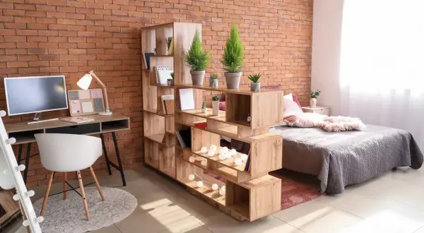 Étagère modulable pour séparer une pièce en deux sans travaux. Elle crée un espace bureau et un coin nuit cosy.