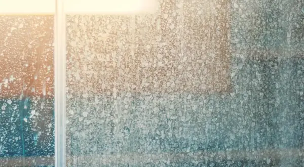 Vitre de douche couverte de traces de calcaire, un défi pour enlever le calcaire vitre douche.