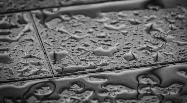 Gouttes d'eau sur un carrelage qui se décolle, signe d'une humidité persistante.
