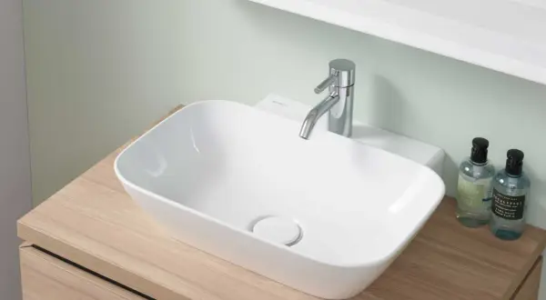 Lavabo blanc moderne sur meuble en bois, robinetterie chromée. La hauteur du lave-main wc est idéale pour un usage confortable.