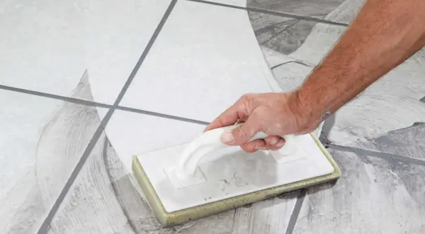 Main tenant, quand nettoyer carrelage après joint, utilise une éponge pour enlever l'excès de mortier.